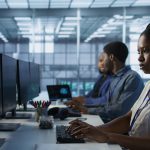Portrait of smiling engineer hearing podcasts to make time pass faster while working in server farm to optimize it for data processing requirements. Happy woman listens songs in data center, camera A